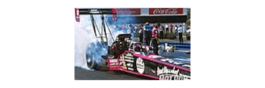 A drag racing car emits smoke as it prepares to launch.