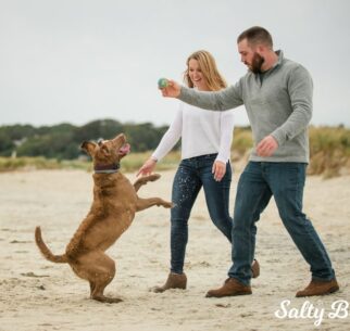 A couple play with their dog on the beach